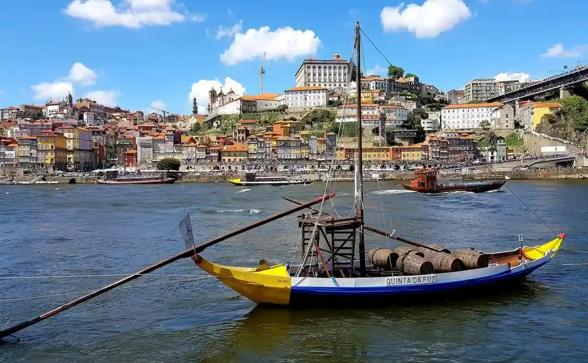 Traditional wooden rabelo boat with barrels of port on the river in front of Porto old town.