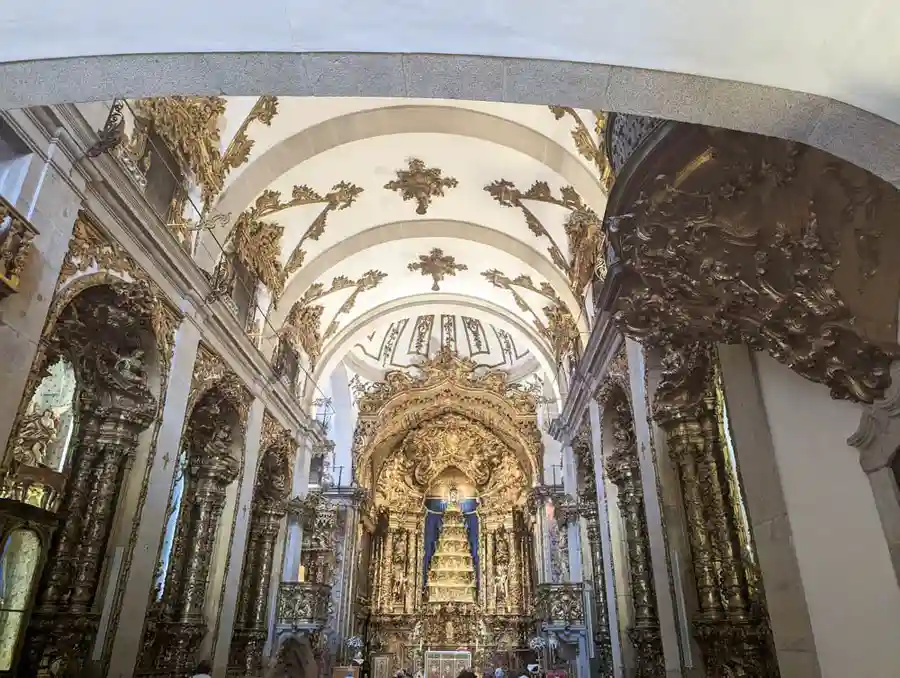 Ornately decorated pillars and dome, and gold altar inside Igreja do Carmo church.