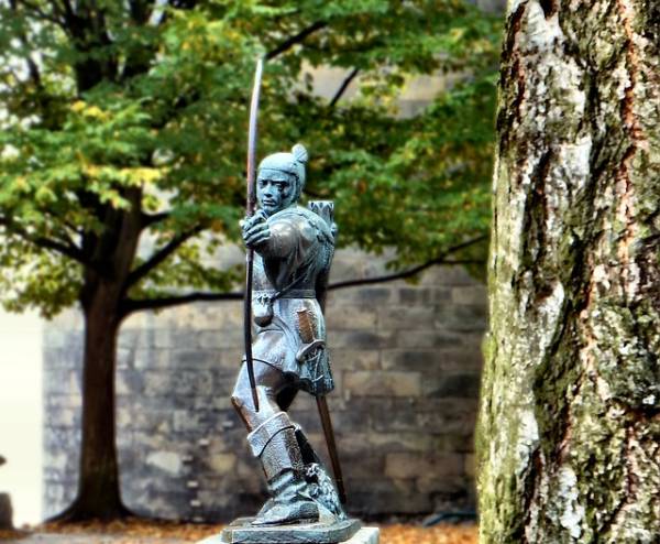 Robin Hood archer statue by old stone wall in Nottingham, England.