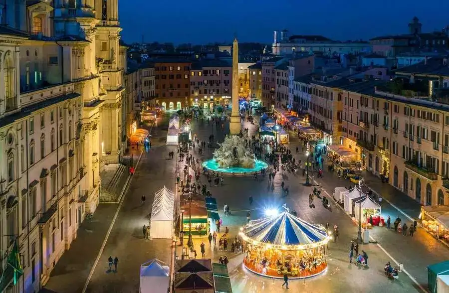 Evening view of a carousel and Christmas market in Rome's Piazza Navona.