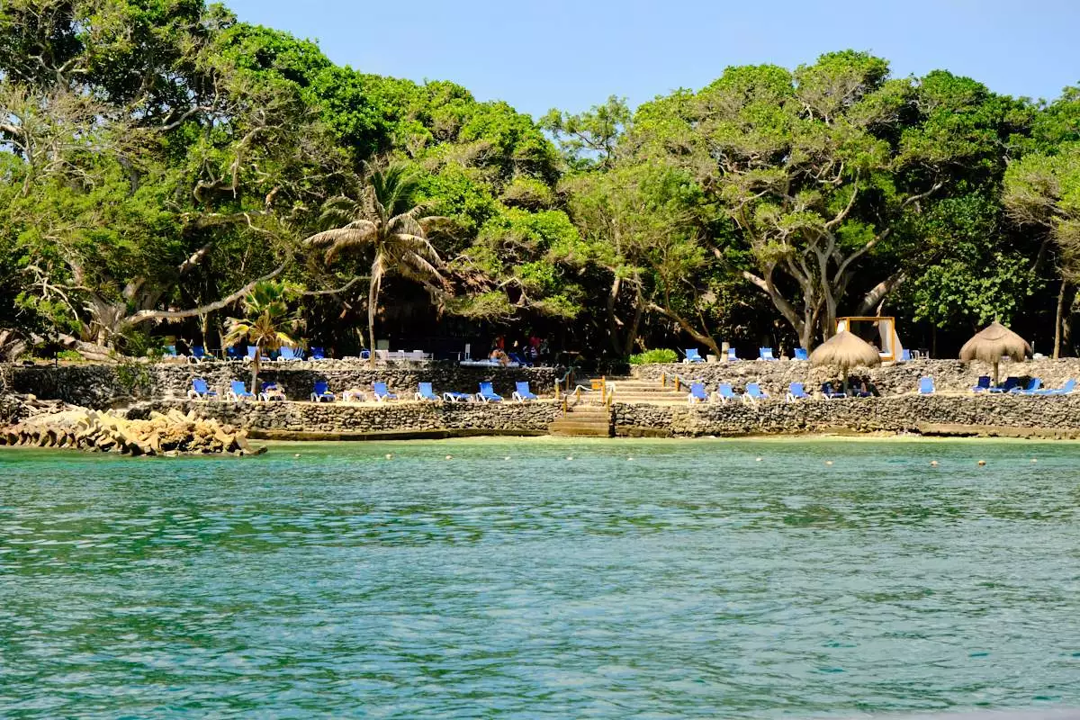 Trees on an island with sun loungers beside the turquoise Caribbean Sea.