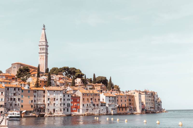 Rovinj church spire and traditional houses beside the sea in Croacia.