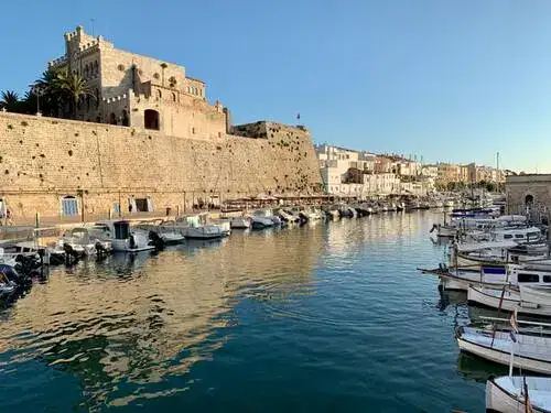 Sailing boats moored in channel with walled fort in background.