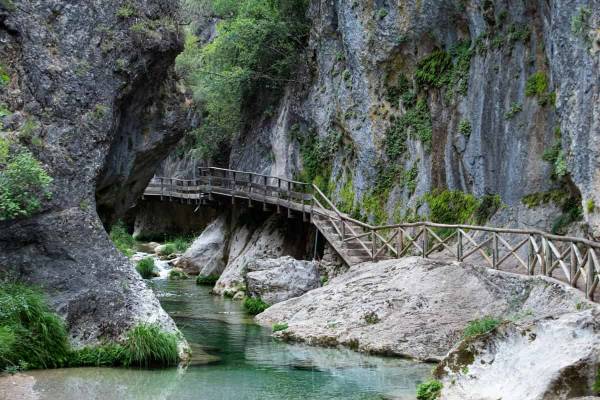 Wooden walkway by rocks and natural spring water pool.