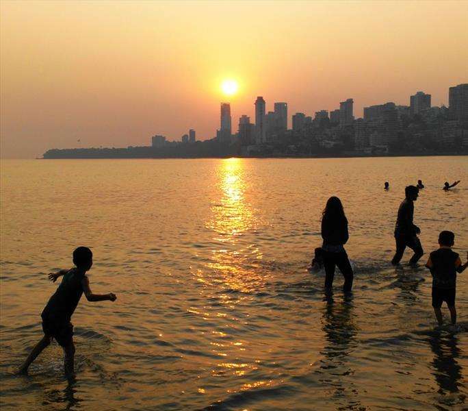 A golden sunset over Mumbai city beach in India.