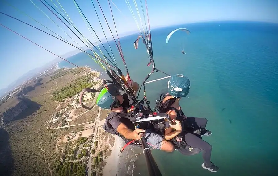 Man and woman tandem paragliding in Alicante over Spain's Mediterranean coast.