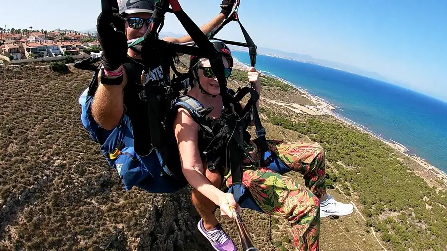 Pilot and woman tandem paragliding in Alicante over Santa Pola coastline.