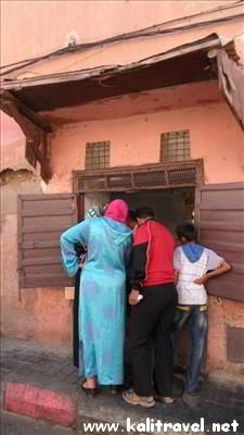 People shopping at a rudimentary food kiosk in Marrakesh medina.