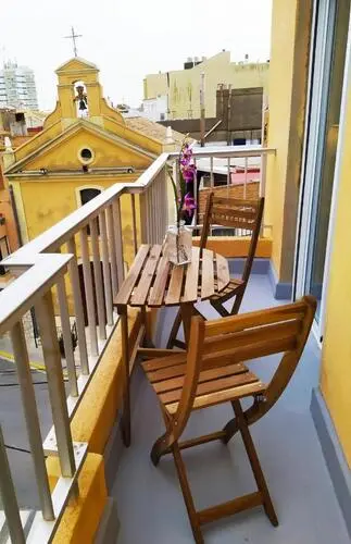 Silla y mesa de madera en el balcón de Hostal El Perelló con visitas al iglesia.