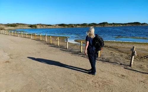 Mujer paseando por sendero de arena a lado de Estany del Pujol lago. 