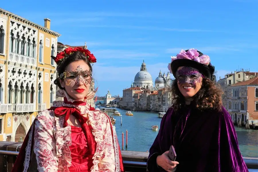 2 women wearing carnival masks on a tour of Venice.