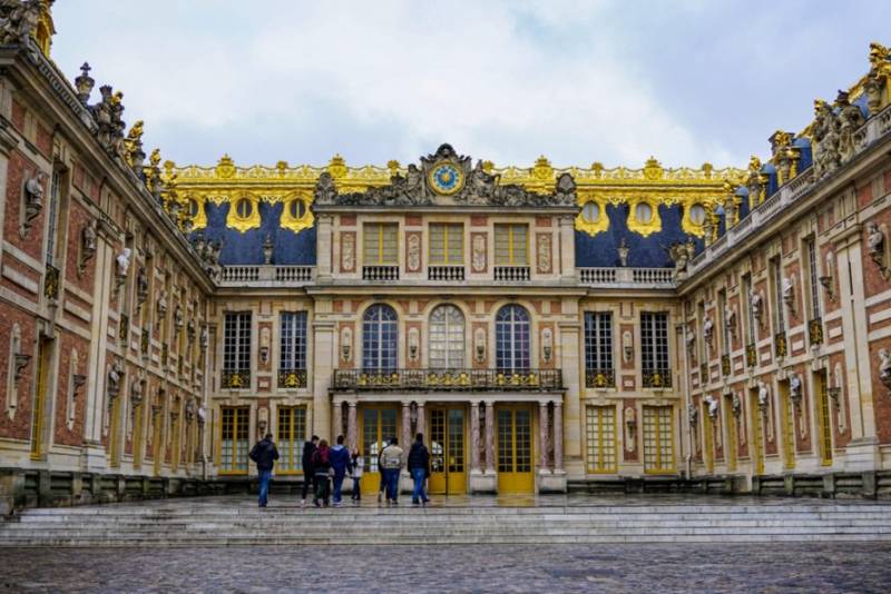 Ornate gold-topped façade of Versailles Palace courtyard.