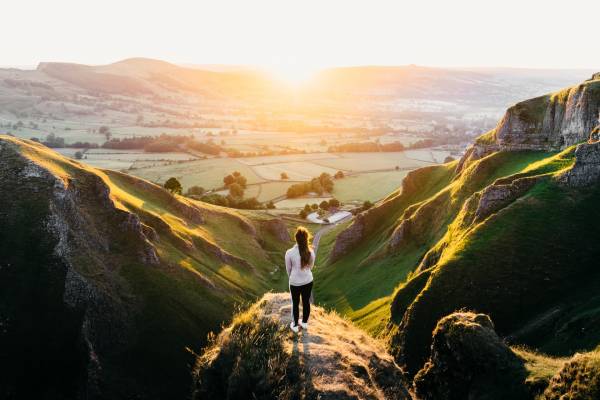 Woman looking at the sun rise over Hope Valley in the Peak District.